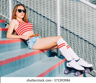 Beautiful Young Blond Woman Standing On The Stairs In Shorts, T-shirt With Sunglasses. The Feet High Socks And Roller Skates Quads Derby. Warm Sunny Summer Evening.