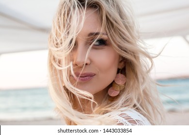 beautiful young blond woman's hair develop in the wind. the model wearing boho style clothes, white  bohemian cape and juverly. girl enjoys freedoom and travel 