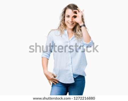 Beautiful young blonde business woman over isolated background doing ok gesture with hand smiling, eye looking through fingers with happy face.