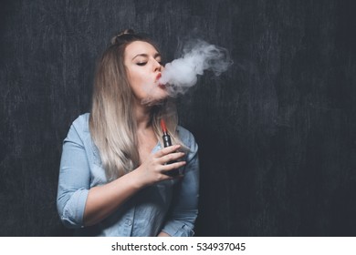 Beautiful young blonde girl smokes electronic cigarette