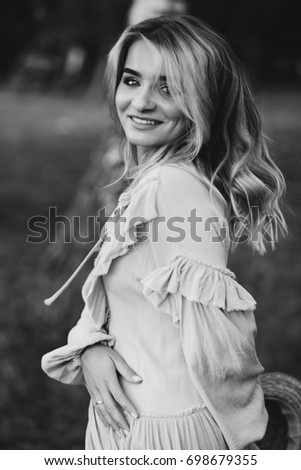 Beautiful young blonde girl at vintage dress and hat have fun at park