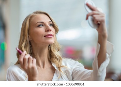 Beautiful Young Blonde Holding Her Lipstick And Looking Into A Compact Mirror At Her Make-up