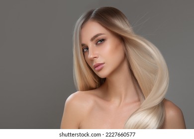 Beautiful young blonde with straight shiny hair. Portrait on a gray background. Hair and makeup - Shutterstock ID 2227660577