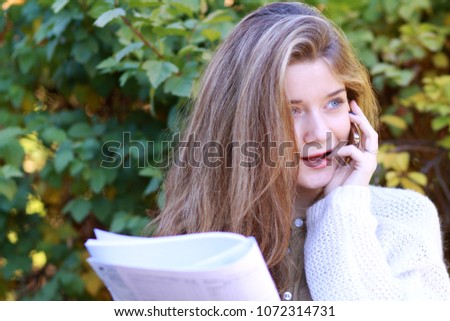 Beautiful young blonde woman calling by phone in autumn park