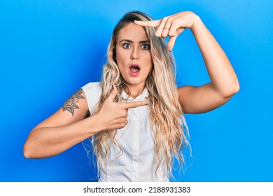 Beautiful young blonde woman doing picture frame gesture with hands afraid and shocked with surprise and amazed expression, fear and excited face. 