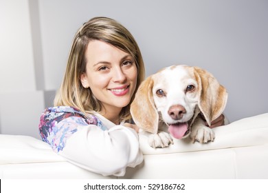 Beautiful young blonde woman with her dog at home