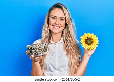 Beautiful young blonde woman holding sunflower seeds an flower smiling with a happy and cool smile on face. showing teeth.  - Powered by Shutterstock