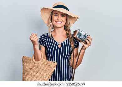 Beautiful young blonde woman holding vintage camera smiling with a happy and cool smile on face. showing teeth.  - Powered by Shutterstock