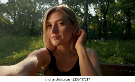 Beautiful young blonde woman makes selfie on camera on hands, POV view. cute girl sits on bench in park and looks into camera or mirror. In nature, slender girl flirts with camera. - Powered by Shutterstock