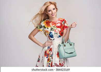 Beautiful Young Blonde Woman In Nice Spring Dress, Handbag Posing In A Studio. Fashion Spring Summer Photo