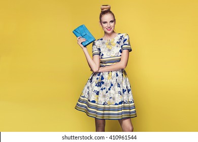 Beautiful Young Blonde Woman In Nice Spring Dress, Posing On Yellow Background In Studio. Fashion Photo, Purse