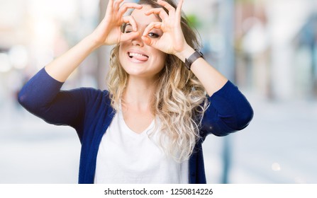 Beautiful young blonde woman over isolated background doing ok gesture like binoculars sticking tongue out, eyes looking through fingers. Crazy expression. - Shutterstock ID 1250814226