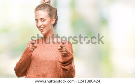 Beautiful young blonde woman over isolated background pointing fingers to camera with happy and funny face. Good energy and vibes.