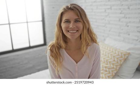 Beautiful young blonde woman smiling in a cozy bedroom with white brick walls and a large window, creating an inviting and serene indoor atmosphere. - Powered by Shutterstock