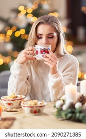 A Beautiful Young Blonde Woman Tastes Christmas Punch, Tea Mulled Wine Or Coffee.