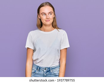 Beautiful Young Blonde Woman Wearing Casual White T Shirt Smiling Looking To The Side And Staring Away Thinking. 