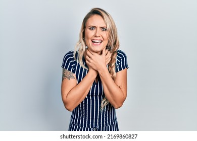 Beautiful young blonde woman wearing casual striped dress shouting and suffocate because painful strangle. health problem. asphyxiate and suicide concept. 