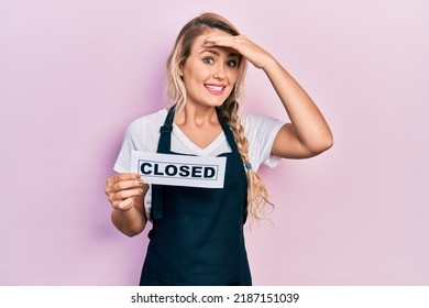 Beautiful Young Blonde Woman Wearing Waitress Apron Holding Closed Banner Stressed And Frustrated With Hand On Head, Surprised And Angry Face 