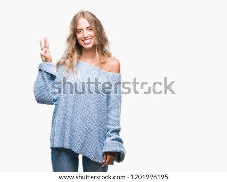 Beautiful young blonde woman wearing winter sweater over isolated background showing and pointing up with fingers number three while smiling confident and happy.