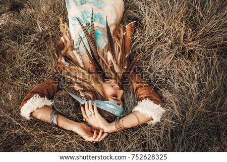 beautiful young boho girl in jacket lying down on grass