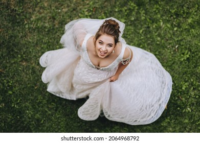 A beautiful, young bride dances and whirls against a background of green grass, holding on to a white dress. Wedding portrait, photography. - Shutterstock ID 2064968792