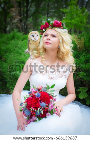 beautiful young bride with peonies in her hair and the owl on his shoulder. wedding concept.