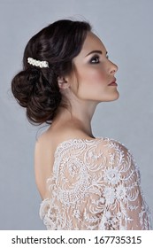 Beautiful young bride with wedding makeup in romantic lace dress on studio background