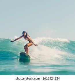 Beautiful young brunette girl in a bikini swimsuit ride wave. Sporty surfer woman surfing in Mauritius in the Indian Ocean on the background of blue sky, clouds and transparent waves. Outdoor Active. - Powered by Shutterstock
