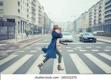 Beautiful young brunette with hat posing in the city streets