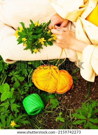 Beautiful young brunette loves needlework, feeling happy and relaxed in the park. Magic lighting. Yellow and green colors