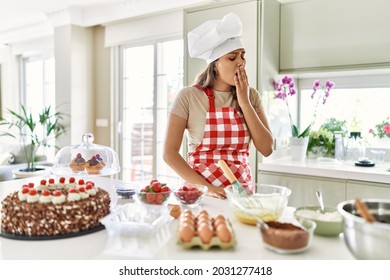 Beautiful young brunette pastry chef woman cooking pastries at the kitchen bored yawning tired covering mouth with hand. restless and sleepiness. 