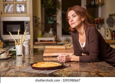 Beautiful Young Brunette Woman In Casual Outfit Cooking In The Kitchen In Her Home. Luxury Rich Interior