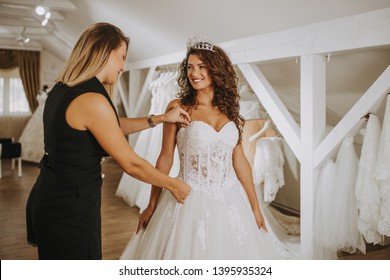 Beautiful young brunette woman choosing wedding dress in a bridal salon.