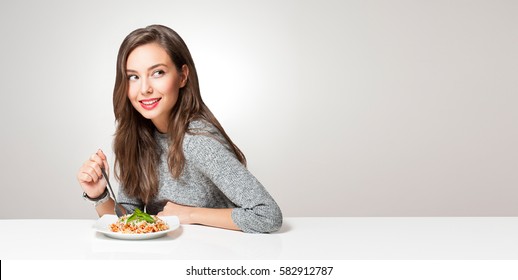 Beautiful young brunette woman eating Italian meal.