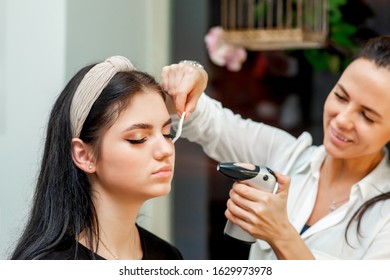 Beautiful Young Brunette Woman Receiving Airbrush Makeup By Makeup Artist.