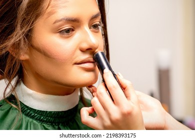 Beautiful Young Brunette Woman Receiving Makeup With Stick Concealer On Her Face In A Beauty Salon