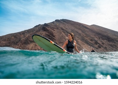 Beautiful young brunette woman surfing in fuerteventura
