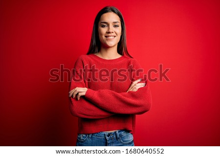 Beautiful young brunette woman wearing casual sweater standing over red isolated background smiling with happy face winking at the camera doing victory sign. Number two.