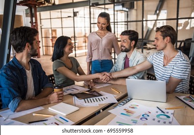 Beautiful Young Business People In Casual Clothes Are Communicating And Smiling While Working In Office, Man And Woman Are Shaking Hands