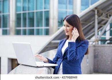 Beautiful young business woman calling by phone on the summer street