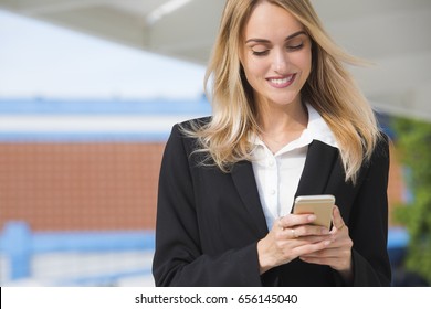 Beautiful Young Business Woman Executive Is Using An Application In Her Smart Phone To Check Email Or Send A Text Message