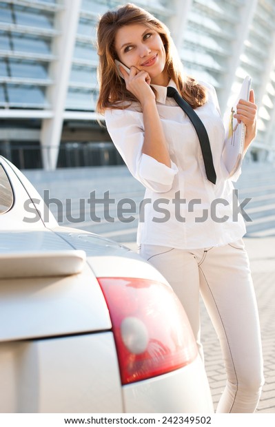 Beautiful young business woman with\
magazine talking on the phone. City business woman working /\
talkative woman in a white button down shirt with black tie\
