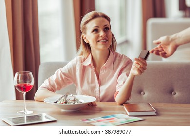 Beautiful Young Business Woman Is Paying With A Credit Card For Business Lunch At The Restaurant