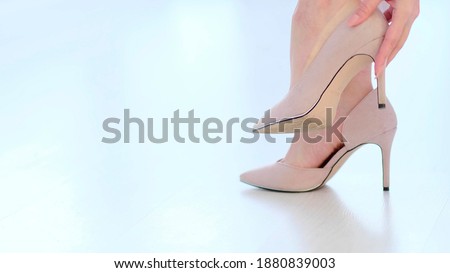 Beautiful young business woman taking her shoes off after a long day. pastel colors, soft focus