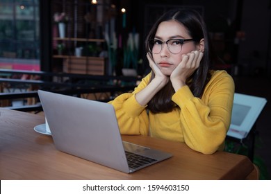 A beautiful young business woman in a yellow sweater sits at a coffee shop, looking disappointed with the past performance that was not what he expected by looking at the report online. - Shutterstock ID 1594603150