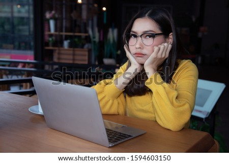A beautiful young business woman in a yellow sweater sits at a coffee shop, looking disappointed with the past performance that was not what he expected by looking at the report online.