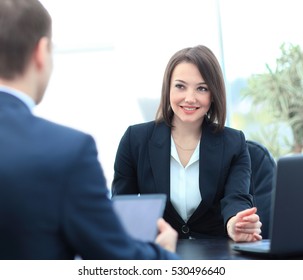 Beautiful young businesswoman conducting a job interview seated at her desk