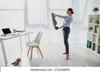 beautiful young businesswoman holding yoga mat in office - Powered by Shutterstock