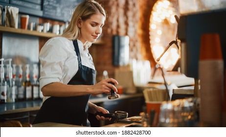 Beautiful Young Caucasian Barista with Blond Hair is Making a Cup of Fresh Coffee in a Cafe. Happy and Smiling Bar Employee Posing while Working in a Cozy Loft-Style Coffee Shop Restaurant Counter. - Powered by Shutterstock