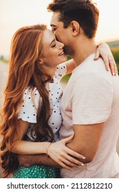 Beautiful young caucasian couple embracing and smiling while standing outdoors. Beautiful summer landscape. Summer vacation. - Shutterstock ID 2112812210